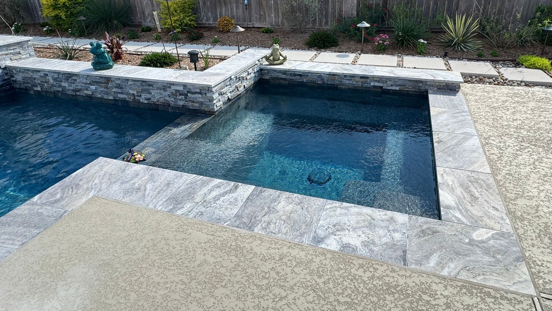Rectangular backyard pool with a raised spa and light stone decking, viewed from above