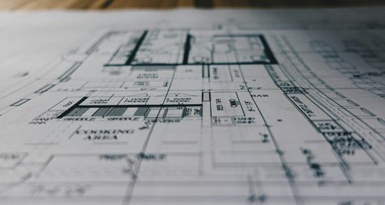 Blueprint drawing of a house floor plan on paper, viewed close up in grayscale