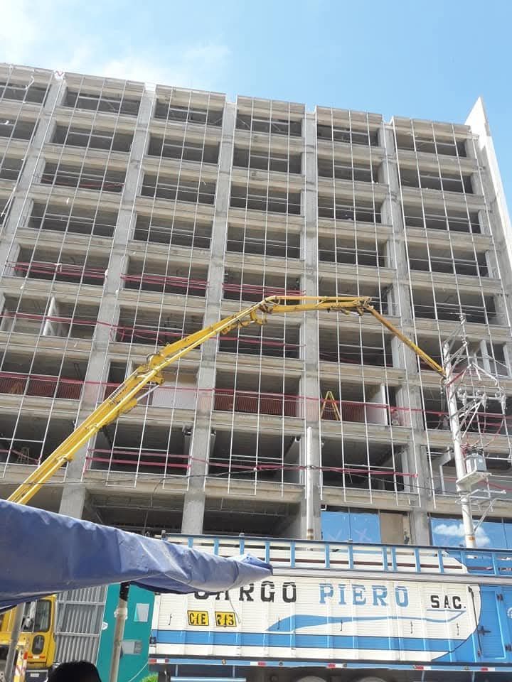Construcción de un rascacielos con una bomba de hormigón. Se ve un trabajador. Cielo azul brillante.