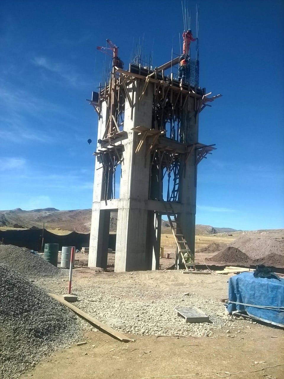 Torre de hormigón en construcción; trabajadores en el nivel superior; cielo azul claro.