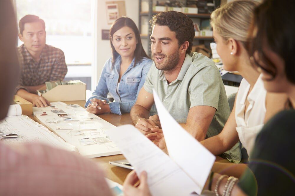 A Group of People Are Sitting Around a Table Having a Meeting — All Round Ground Maintenance in Woolgoolga, NSW
