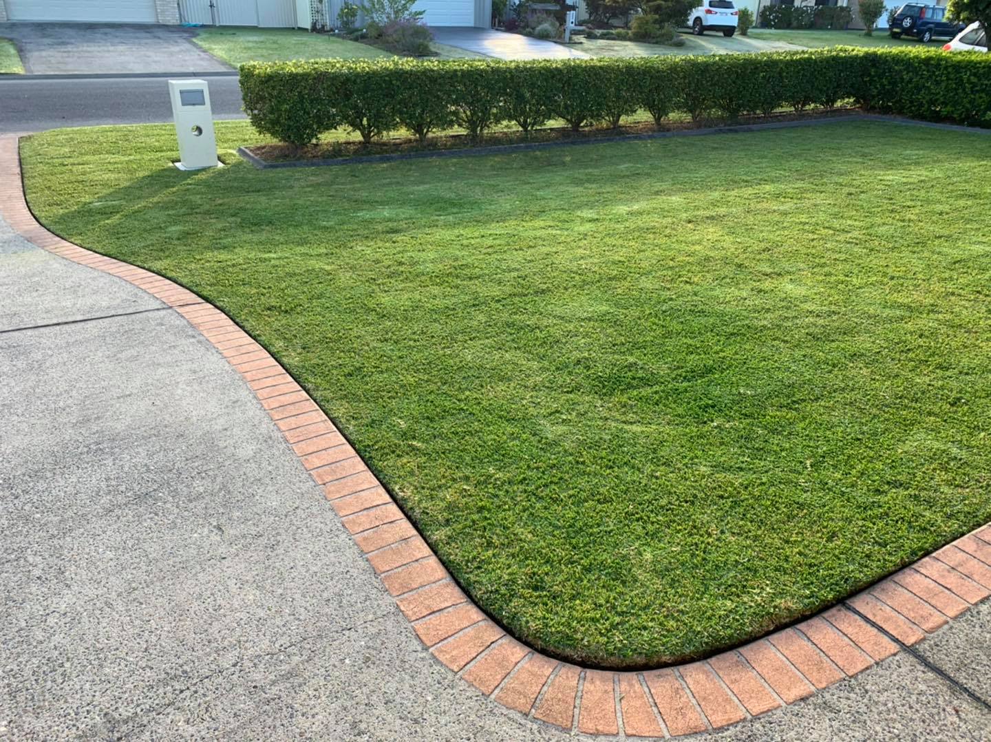 A Lush Green Lawn with A Brick Curb and A Brick Walkway — All Round Ground Maintenance in Mid North Coast, NSW