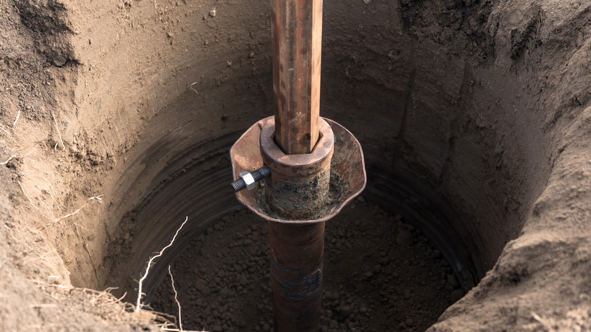 A hole in the ground with a metal pole in it.