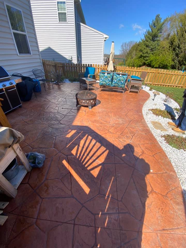 A patio with a grill , chairs , umbrellas and a fire pit.