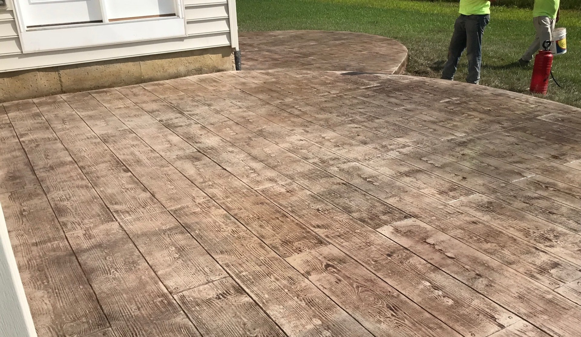 A man is standing on a concrete deck next to a house.