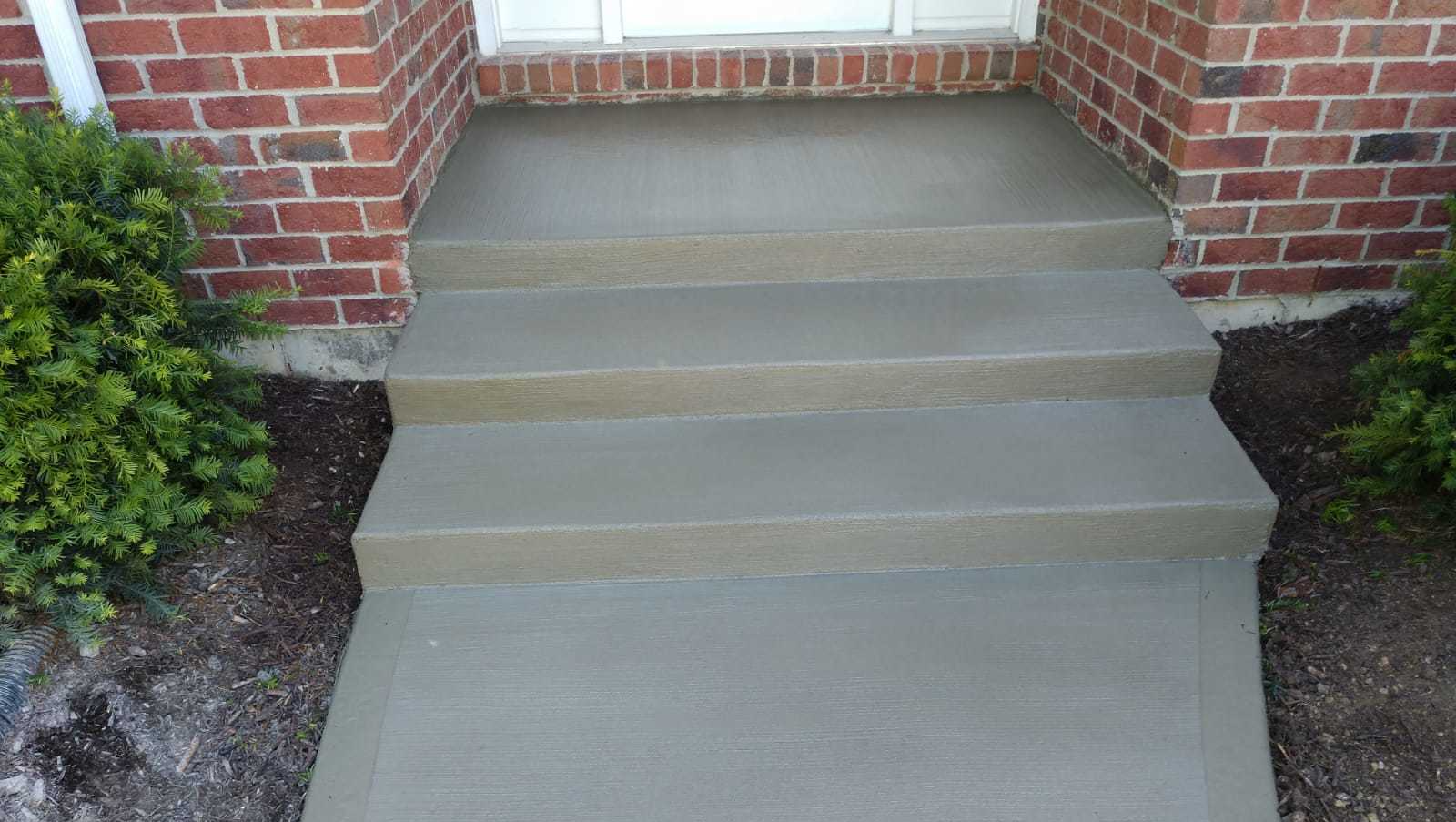 A set of concrete steps leading up to a brick house.