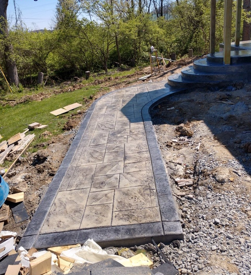 A concrete walkway is being built in a backyard.