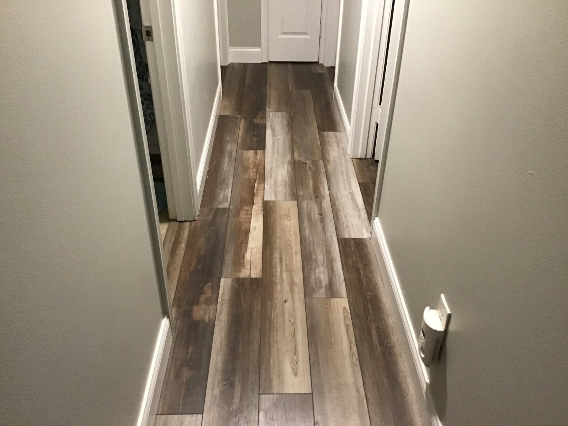 A hallway with a wooden floor and white walls.