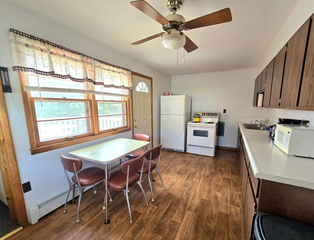 A small kitchen with a table and chairs, an oven, a refrigerator, and cabinets.