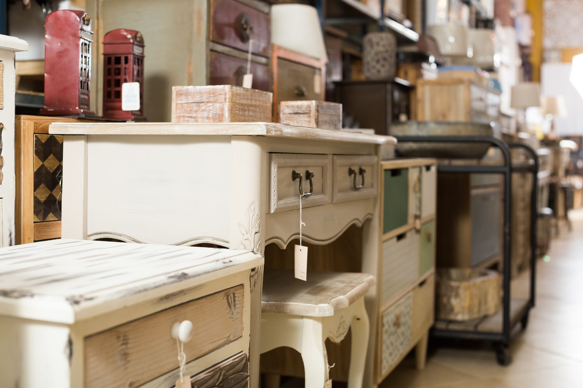 A collection of vintage-style painted wooden furniture, including small desks and drawer units, in a rustic shop display.