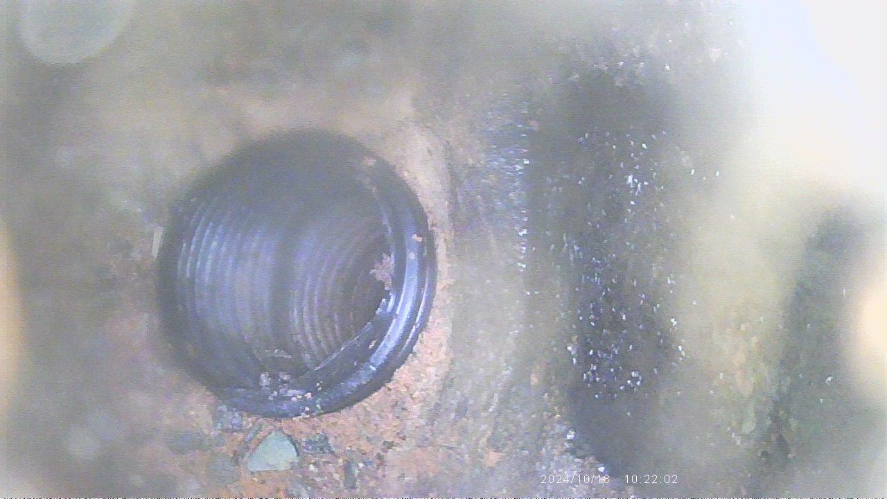 A man is opening a manhole cover in a field.