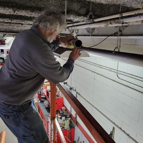 A man is working on a ceiling fan in a garage