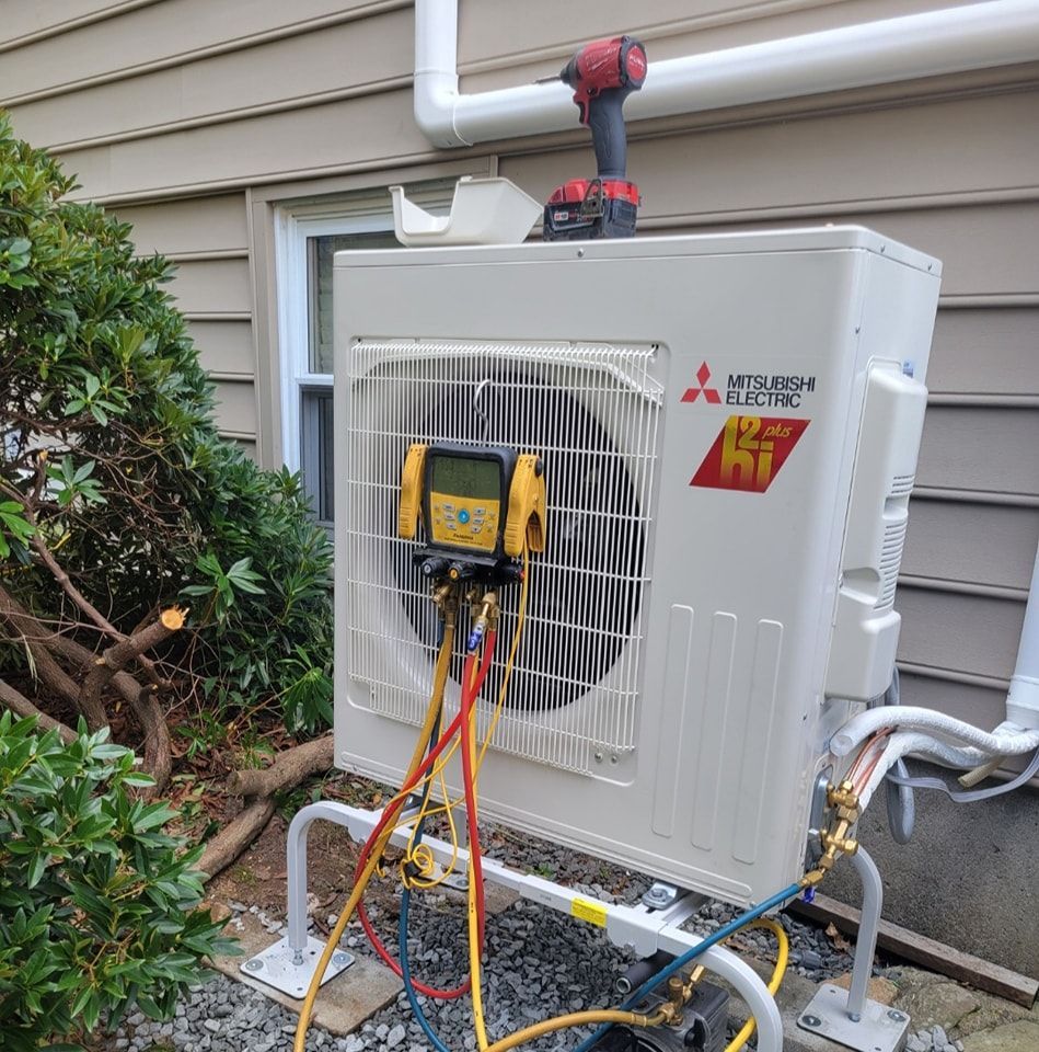 A mitsubishi electric air conditioner is being installed on the side of a house.