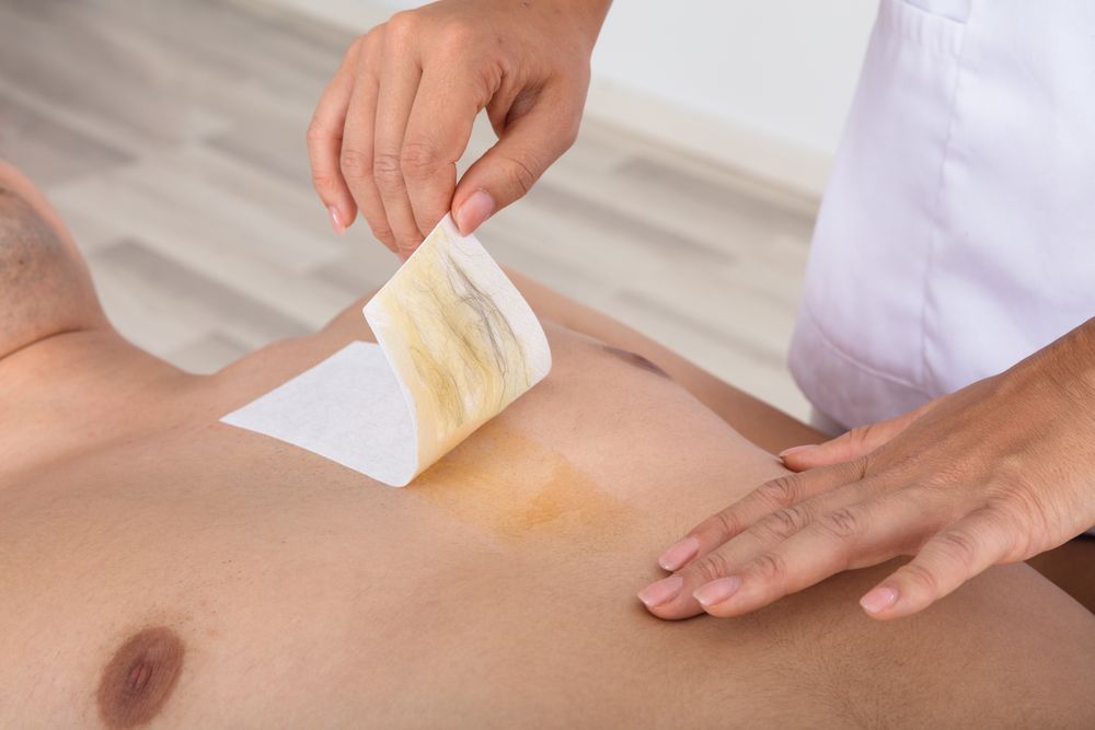 A Person's Chest Being Waxed; Esthetician Peeling a Wax Strip — Sage Spa & Beauty in Mackay, QLD