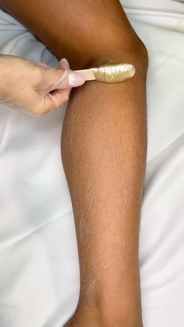 Person Waxing Leg With Spatula, Leg is Covered in Small Hairs, on a White Surface — Sage Spa & Beauty in Mackay, QLD