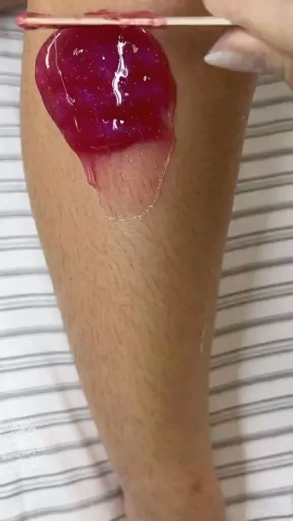 Leg Being Waxed With Pink Wax. a Hand Applies the Wax With a Wooden Stick — Sage Spa & Beauty in Mackay, QLD