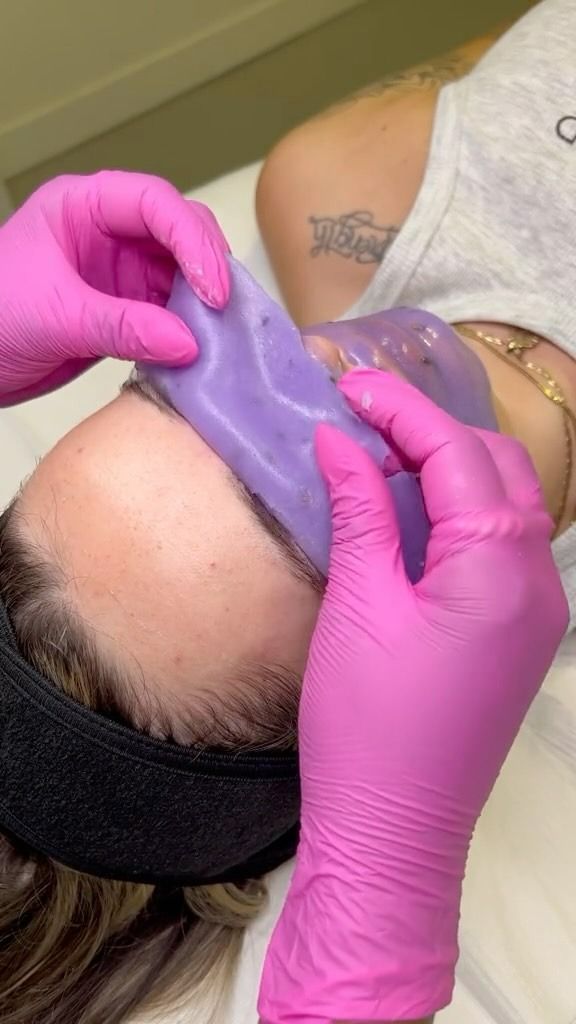Person Receiving a Facial Treatment With a Purple Mask, Hands Wearing Pink Gloves — Sage Spa & Beauty in Mackay, QLD