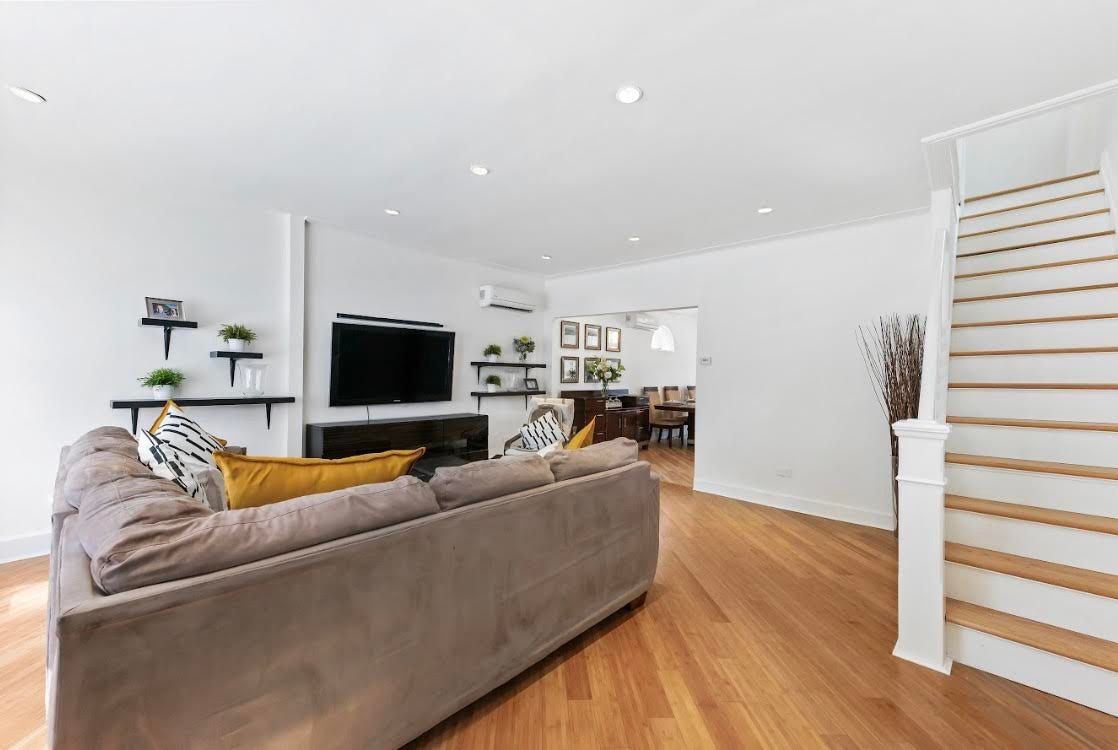 A living room with a couch , television , and stairs.
