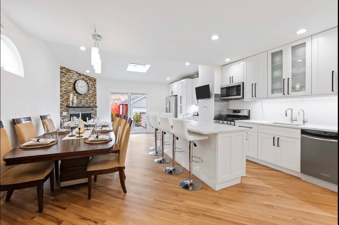 A kitchen and dining room in a house with hardwood floors and white cabinets.
