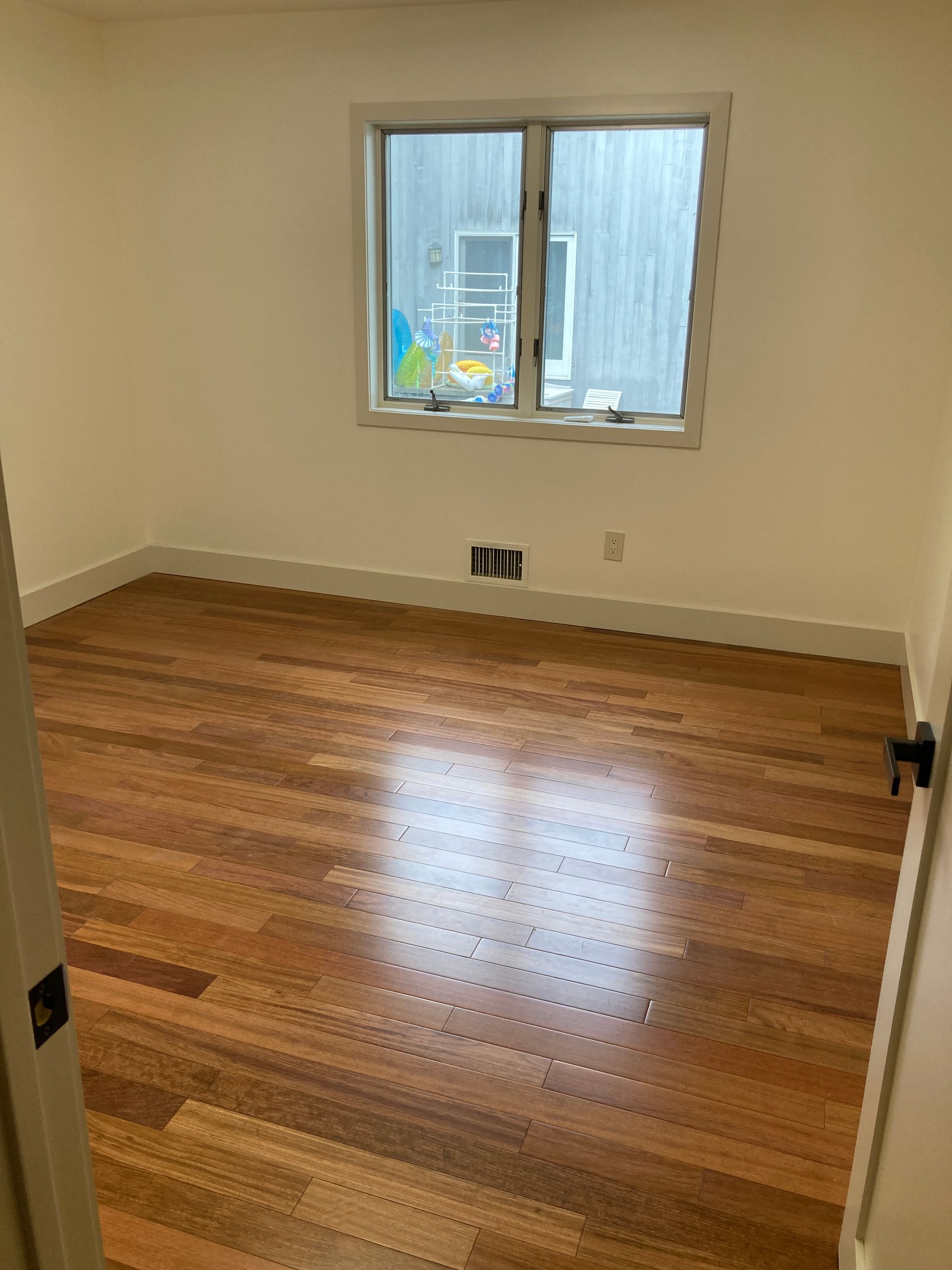 An empty room with hardwood floors and a window.