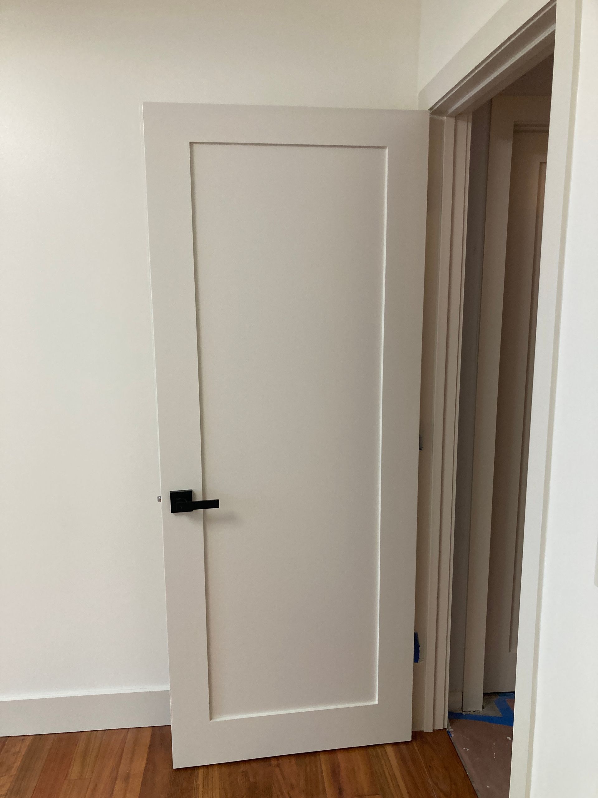 A white door with a black handle is open in a room.