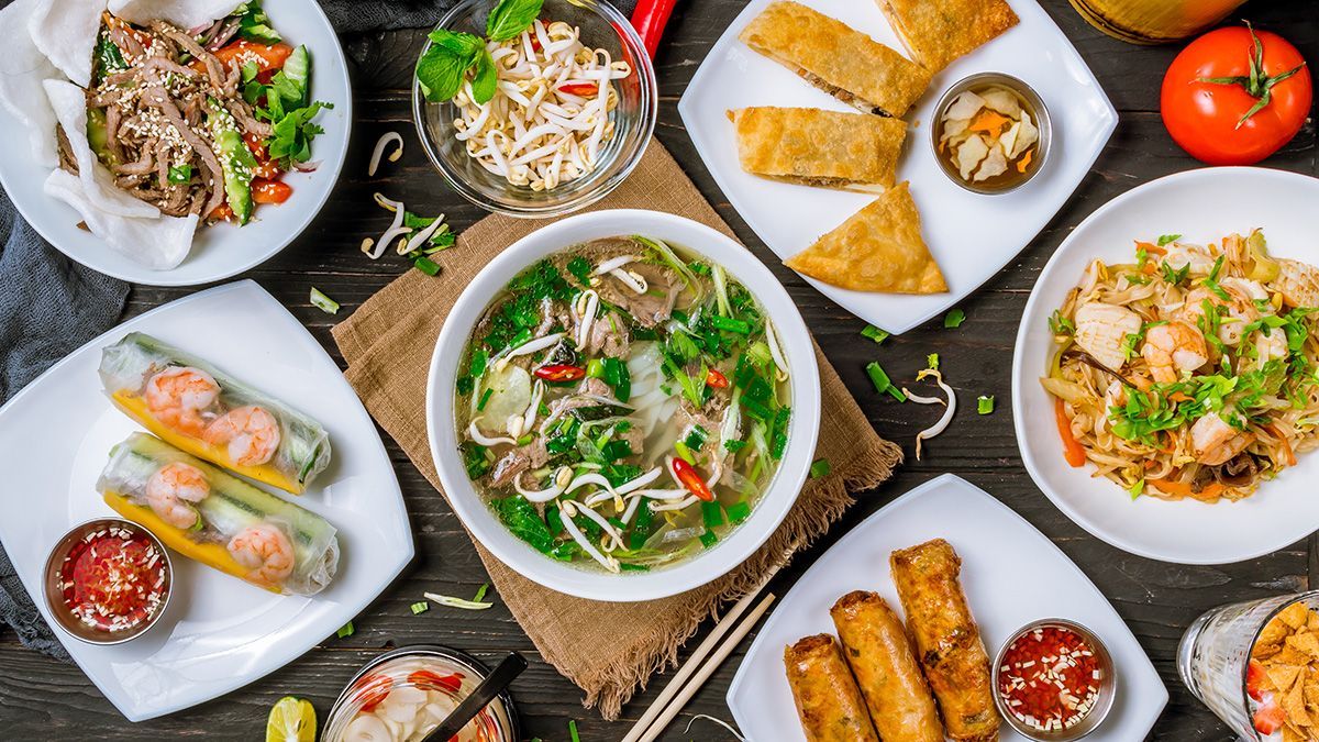 An assortment of Vietnamese dishes including pho, spring rolls, fresh rolls, stir-fried noodles, and