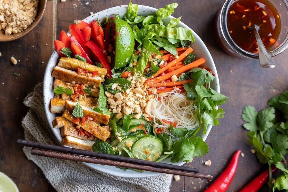 Vegan Vietnamese noodle bowl with tofu, fresh veggies, and herbs.