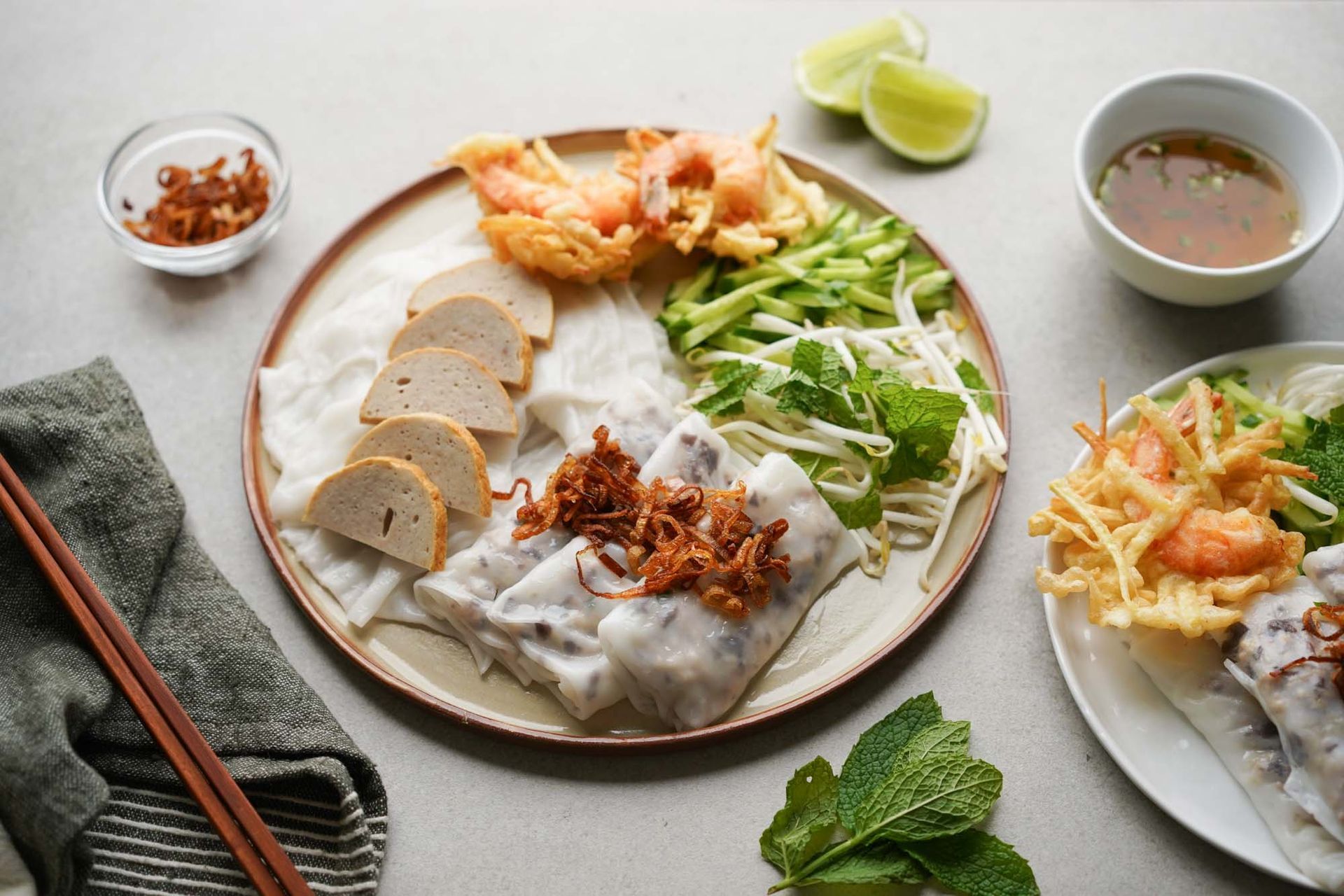 Plate of steamed rice rolls topped with fried shallots and herbs.