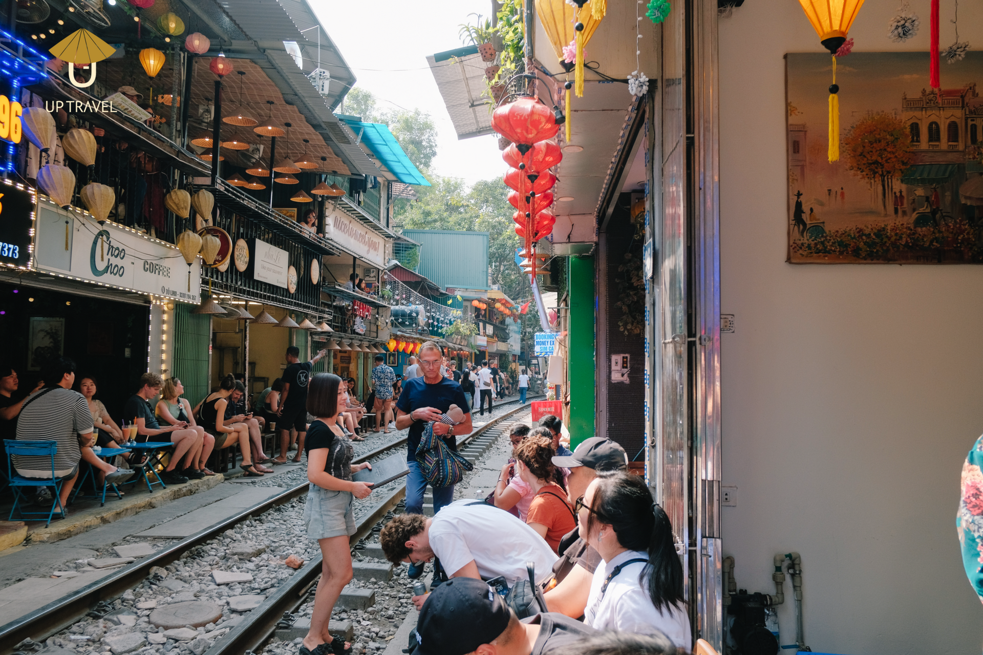 Busy Hanoi street filled with tourists at the Train Street cafés decorated with lanterns.
