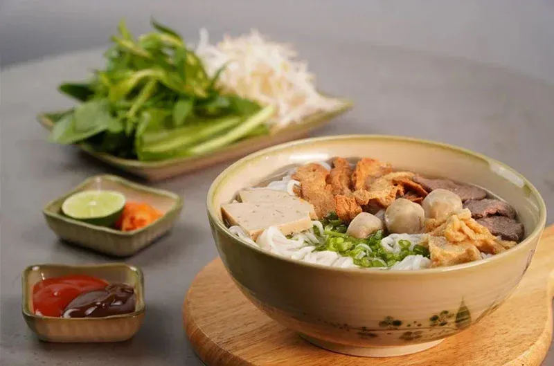 A bowl of Vietnamese vegan pho with fresh herbs and tofu.