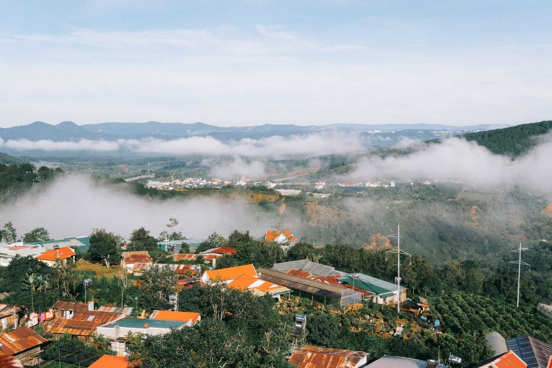 A view of Da Lat from above with fog and red-roofed houses.