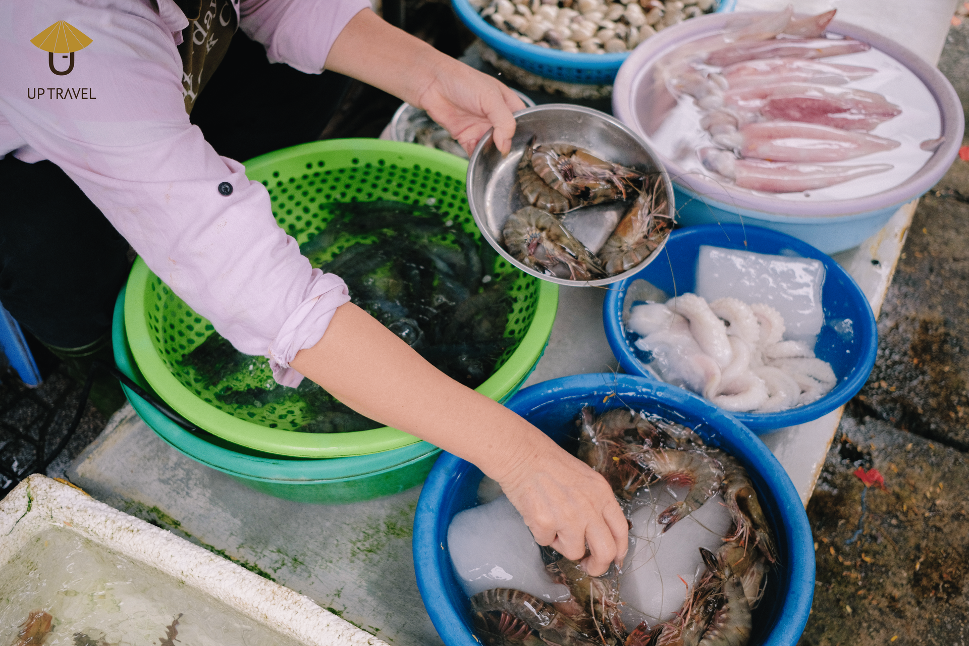 Vietnamese seafood vendor picking shrimp for a customer at the market.