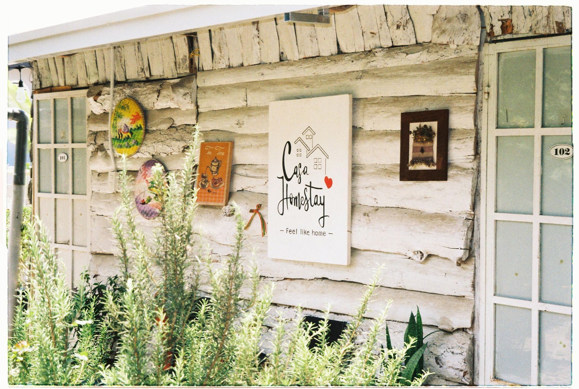 A cozy wooden homestay with a rustic design, featuring a sign that says 