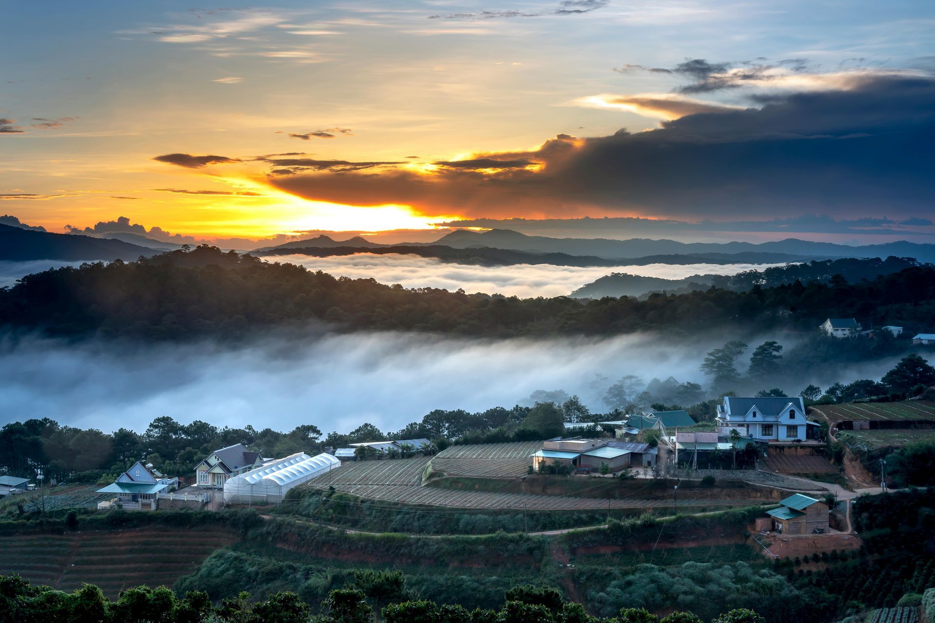 A sunrise over the misty mountains and green farmlands of Da Lat, Vietnam.
