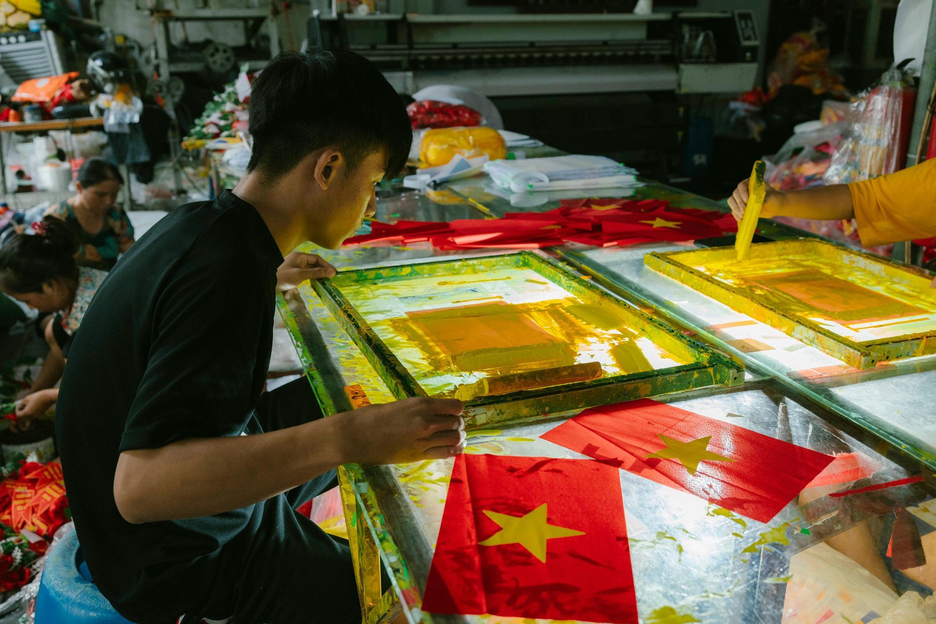 n artisan is meticulously sewing the Vietnamese flag, with a striking yellow star on a red fabric background.