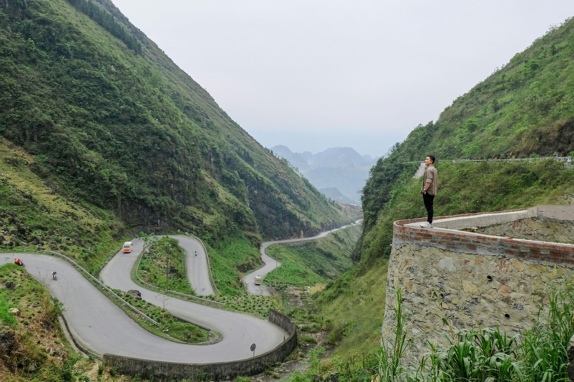 A panoramic view of Ma Pi Leng Pass, with winding mountain roads and a deep green valley below.