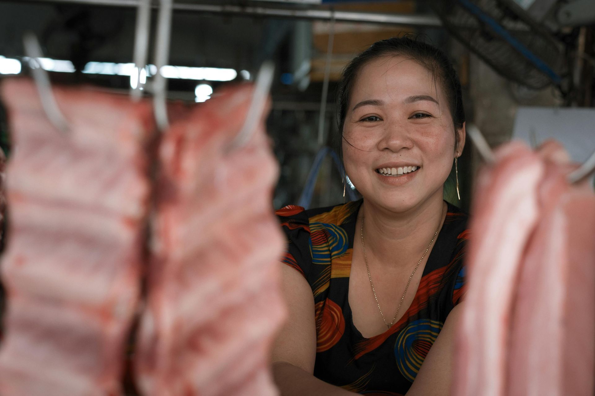 Smiling Vietnamese market vendor selling fresh produce.