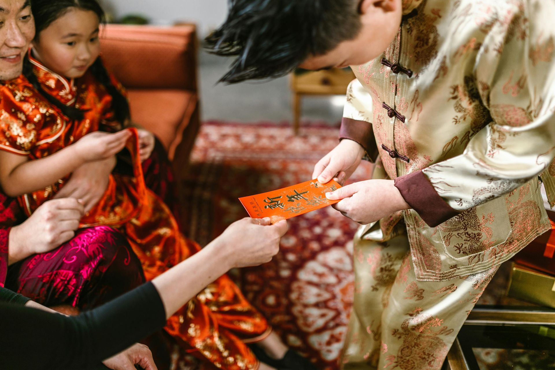 A smiling Vietnamese boy receiving a red envelope during Tet celebrations.