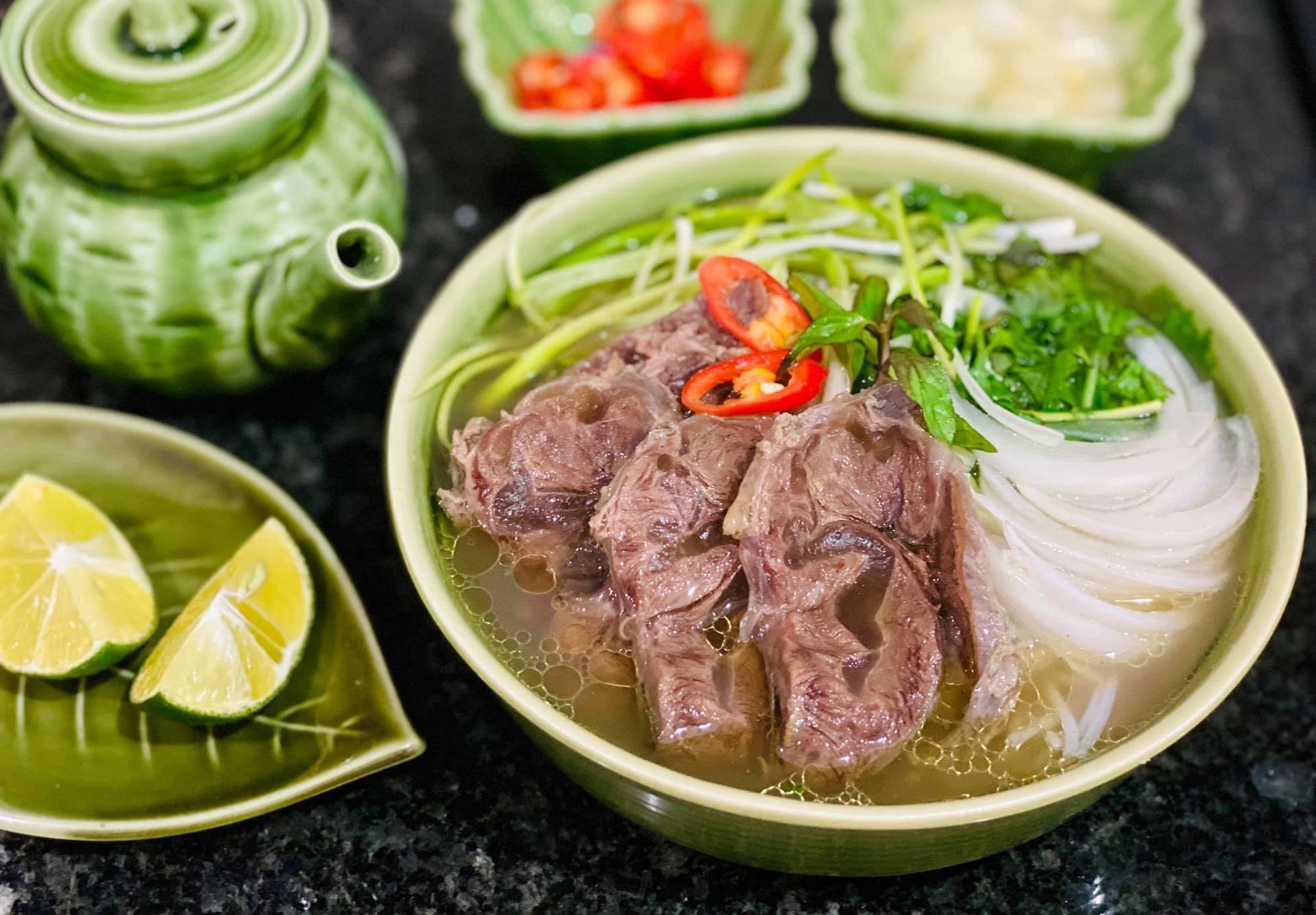Vietnamese beef noodle soup with sliced beef, onion, and herbs.