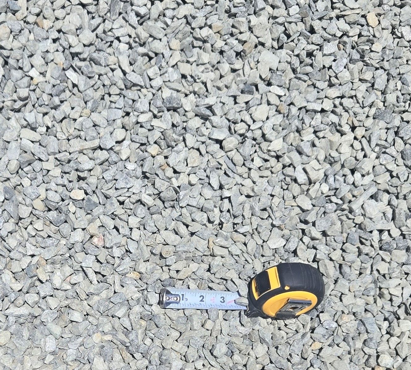 A screwdriver is laying on top of a pile of rocks.