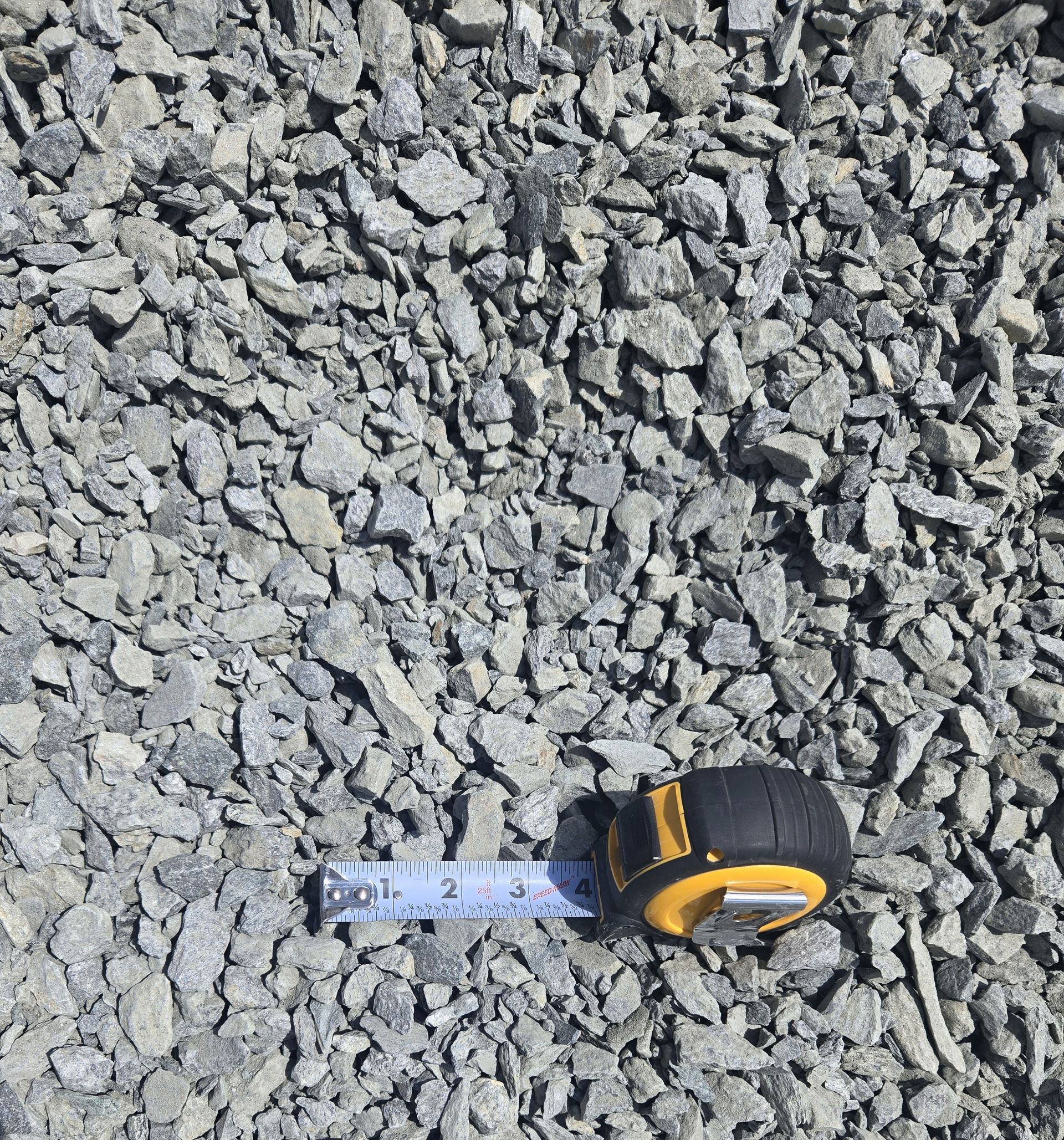 A tape measure is sitting on top of a pile of gravel.