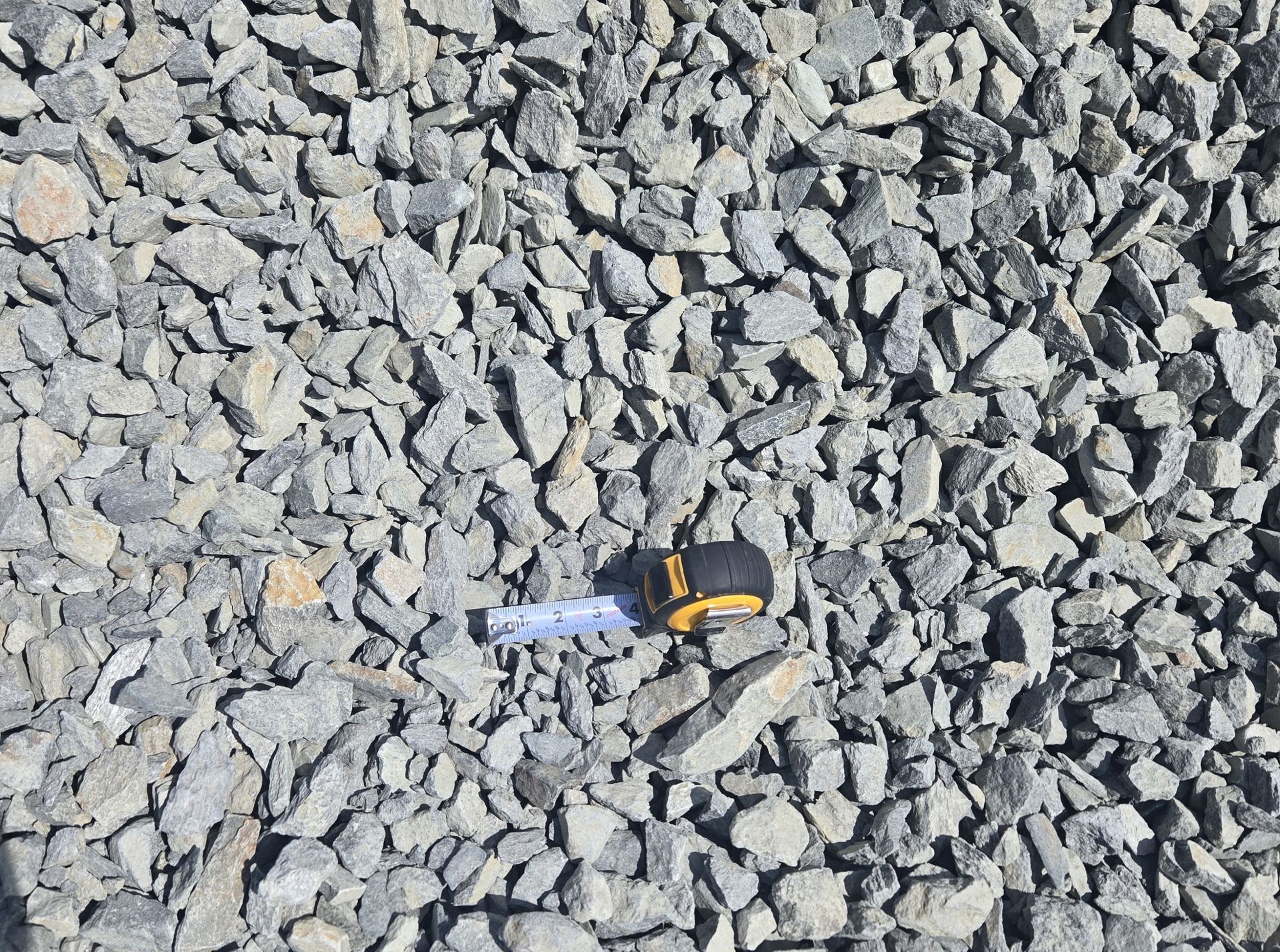 A tape measure is sitting on top of a pile of gravel.