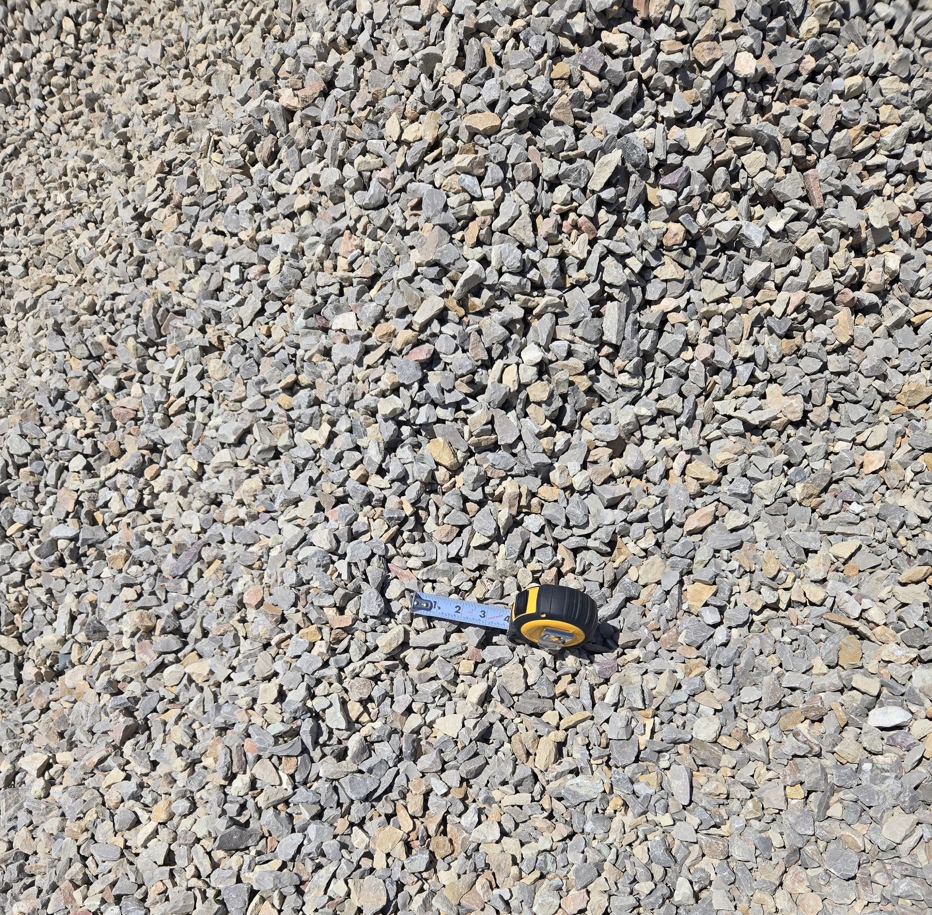 A measuring tape is sitting on top of a pile of gravel.