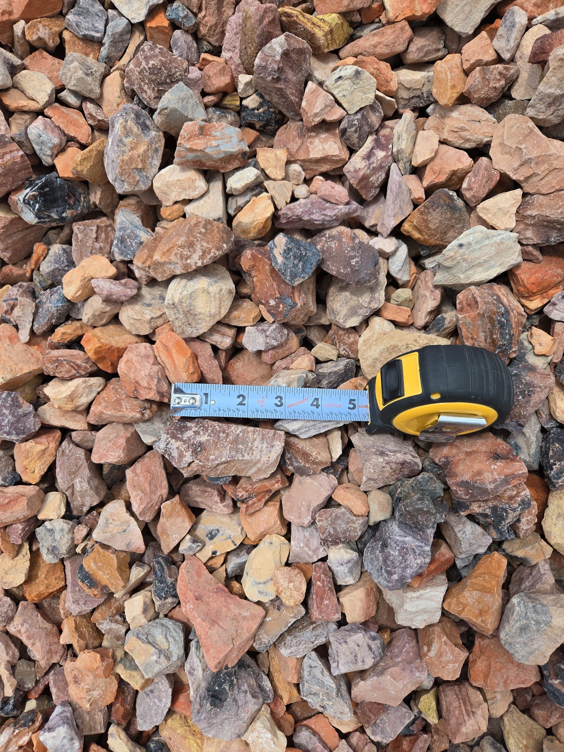 A tape measure is laying on top of a pile of gravel.