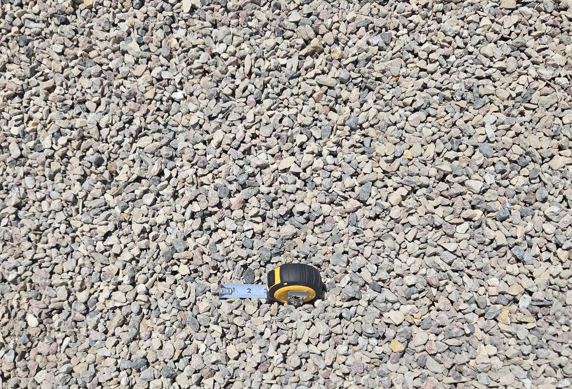 A tape measure is sitting on top of a pile of gravel.