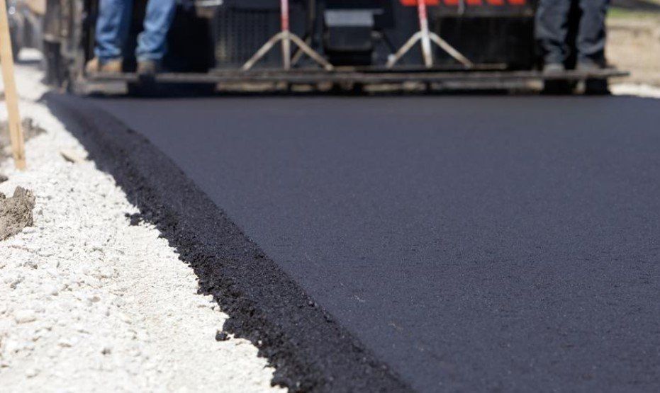 A truck is laying asphalt on a road.