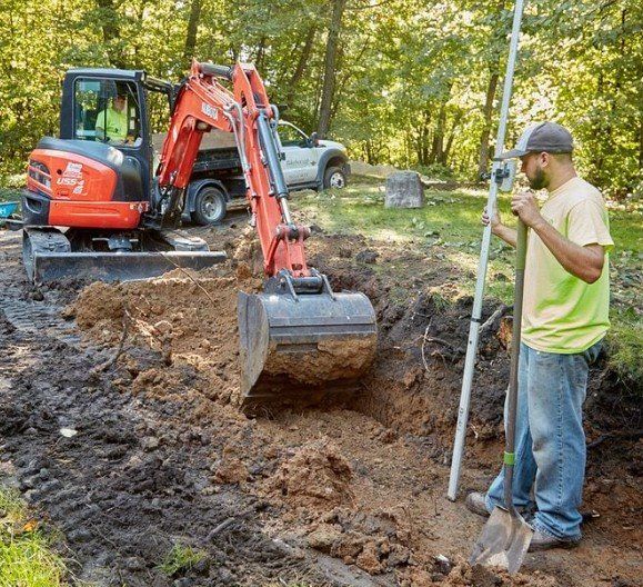 A man is standing in the dirt next to an excavator