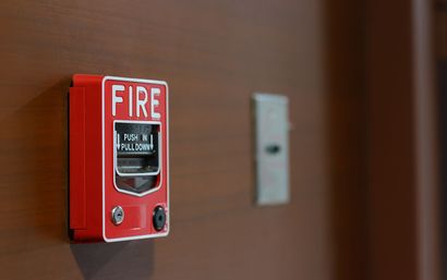 Red fire alarm on a wall beside a metal switch plate