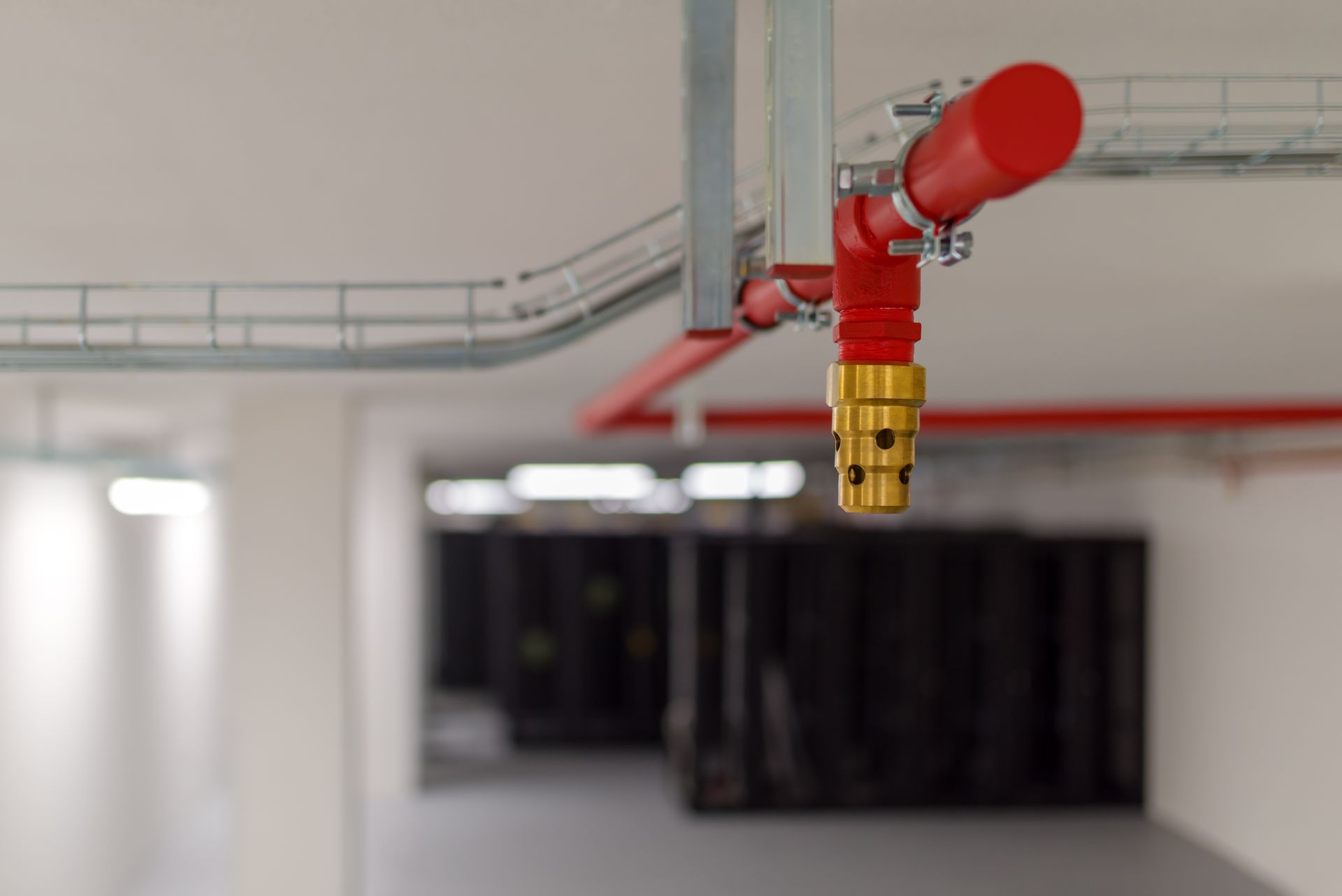 Red fire sprinkler head mounted on a white ceiling in an industrial interior