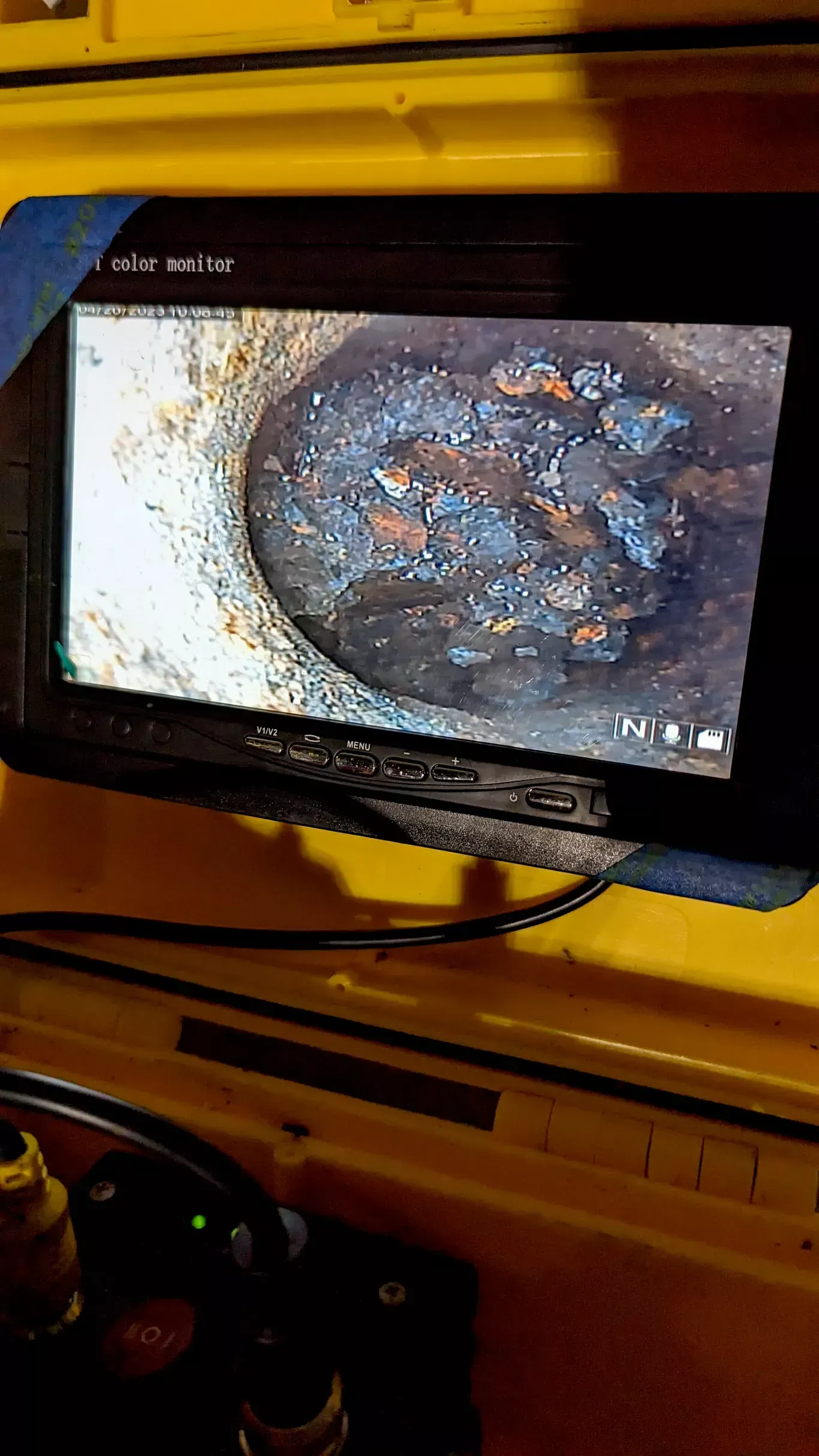Monitor displaying close-up of a corroded pipe interior with rust-colored sections and dark deposits.